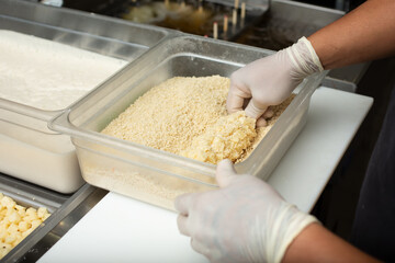 A view of an employee rolling a Korean style rice hot dog in the rice flour, seen at a local restaurant.