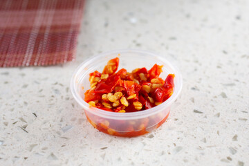 A closeup view of a condiment cup full of minced bird's eye chili.