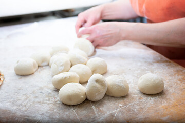Fototapeta na wymiar A view of a worker preparing bread dough balls in a restaurant kitchen setting.