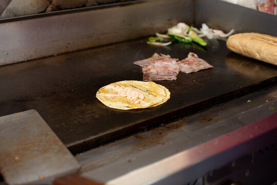 A view of a taco ingredients cooking on a griddle, seen in a restaurant kitchen.
