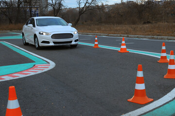 Modern car on driving school test track with traffic cones