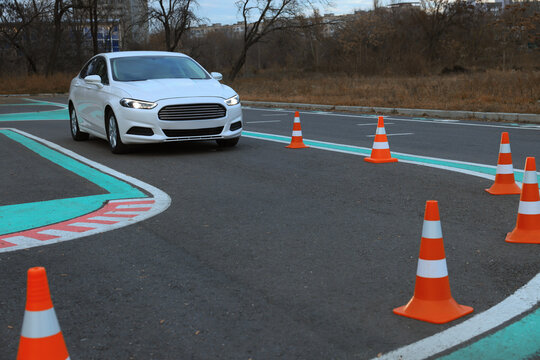 Modern car on driving school test track with traffic cones