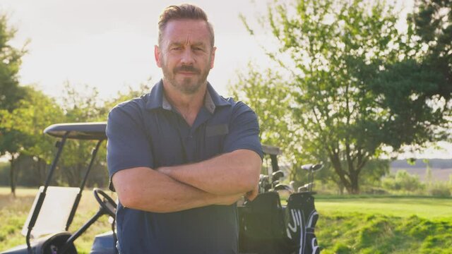 Portrait of smiling mature male golfer standing by buggy on course - shot in slow motion