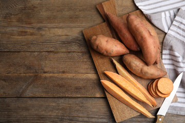 Sweet potatoes and knife on wooden table, flat lay. Space for text