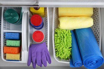 Different cleaning supplies in open drawer, top view