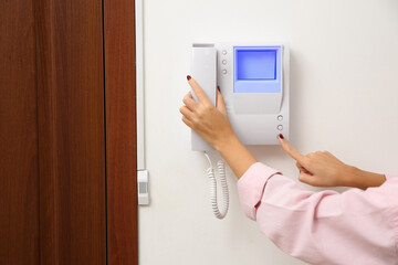 African-American woman pressing button on intercom panel indoors, closeup