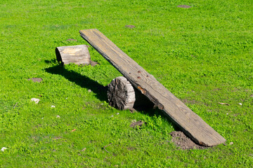 Teeter totter, seesaw made of wooden board and log on a green grass.