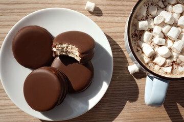 Tasty choco pies and cocoa with marshmallows on wooden table, flat lay