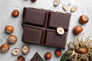 Delicious chocolate and hazelnuts on light table, flat lay