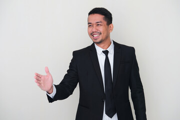 Adult Asian man wearing black suit and tie doing hand shake gesture for agreement
