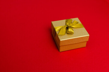Golden gift box on the red background with copy space