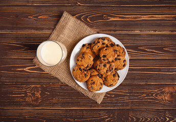 Tasty chocolate chips cookies with milk on wooden table
