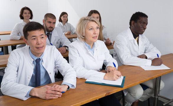 Portrait of focused medics sitting in lecture hall, listening specialty workshop