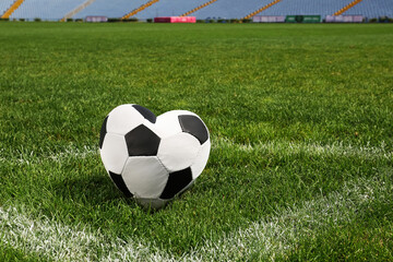 Heart shaped soccer ball on green field at stadium