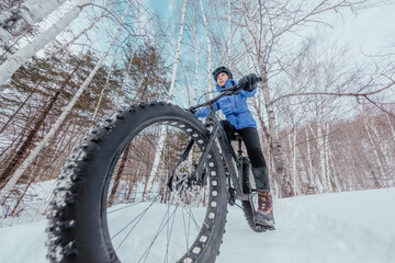 Fat bike in winter. Fat biker riding bicycle in the snow in winter. Close up action shot of fat...