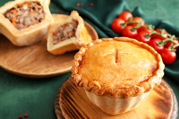 Board with tasty beef pot pie on color background