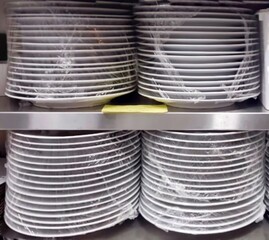Pile of plates in the restaurant. Clean plates wrapped in plastic wrap in the restaurant pantry...