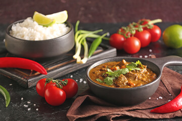 Frying pan with tasty beef curry on dark background