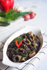 squid cooked in black sauce in a white plate