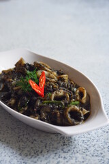 squid cooked in black sauce in a white plate
