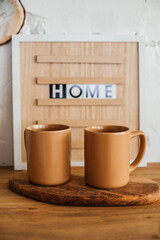 two beige coffee mugs are on the kitchen table