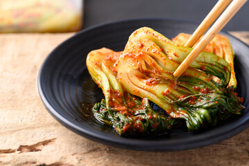Kimchi bok choy eating with chopsticks on wooden background, Homemade Korean fermented side dish...