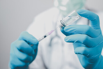 A doctor or scientist in the COVID-19 medical vaccine research and development laboratory holds a syringe with a liquid vaccine to study and analyze antibody samples for the patient.
