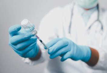 A doctor or scientist in the COVID-19 medical vaccine research and development laboratory holds a syringe with a liquid vaccine to study and analyze antibody samples for the patient.
 - obrazy, fototapety, plakaty