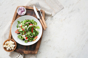 Plate with healthy Greek salad on light background