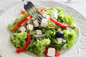Plate with healthy Greek salad on light background, closeup