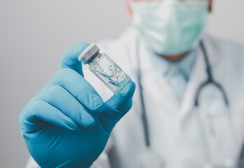 A doctor or scientist in the COVID-19 medical vaccine research and development laboratory holds a syringe with a liquid vaccine to study and analyze antibody samples for the patient.
