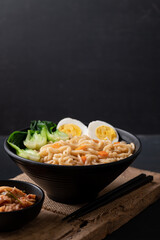 Korean spicy instant noodles soup with bok choy and boiled egg in a bowl eating with kimchi