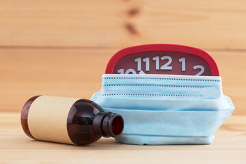 An alarm clock with a mask and a medicine bottle