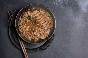 Instant noodles in gray Japanese ceramic lining with black tray, top view.