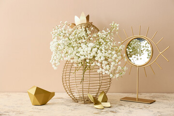 Decorative vase with beautiful gypsophila flowers and mirror on table near color wall