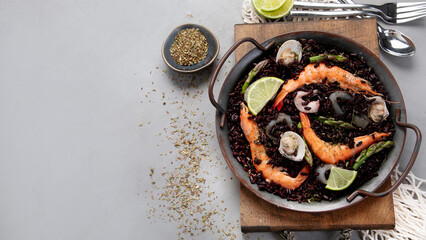Black seafood Paella on gray background.