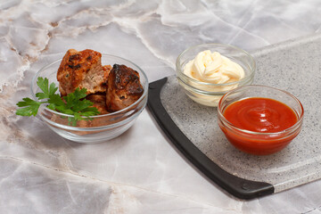 Grilled pork in a bowl with sauces and greens.