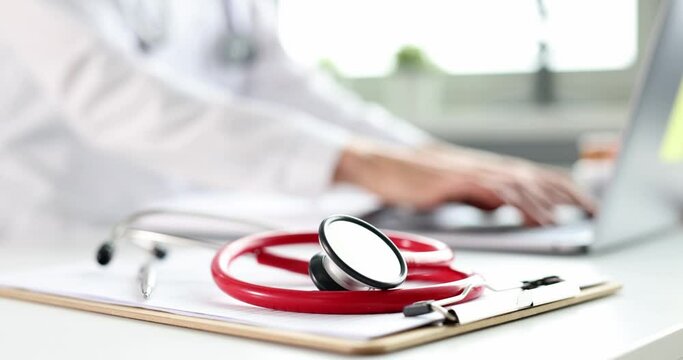 Red stethoscope background typing doctor on laptop