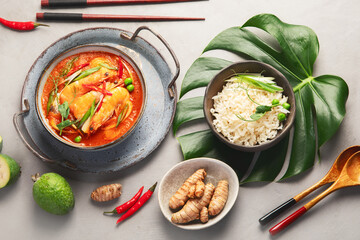 Red curry with chicken in bowl on light gray background.