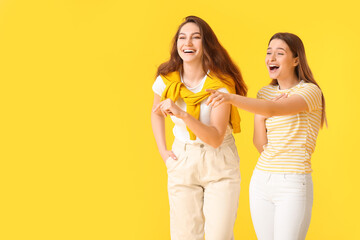 Young gossiping women on color background