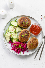 Balanced diet, chicken rissoles, sauerkraut, cucumber salad, ketchup. Top view, copy space.