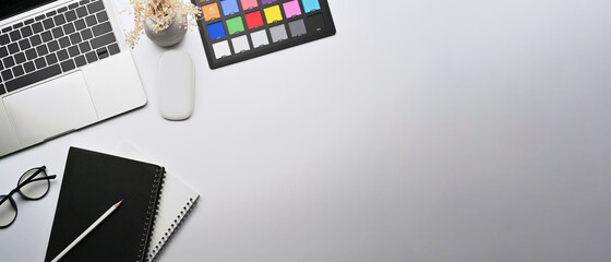 Top view creative workspace with laptop computer, notebook, glasses and color swatch.