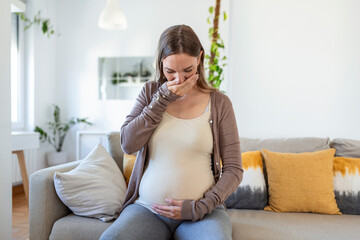 young pregnant woman suffering from toxicosis at home. maternity lady having morning sickness...