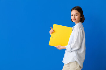 Beautiful young woman with folder on color background