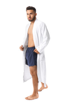 Handsome young man in underwear and bathrobe on white background