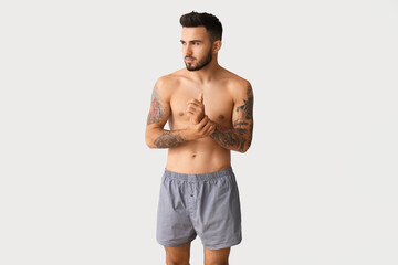Handsome young man in underwear on light background - obrazy, fototapety, plakaty