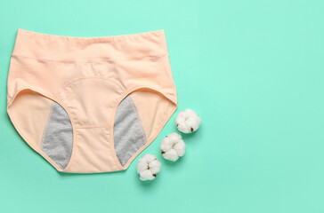 Period panties and cotton flowers on color background
