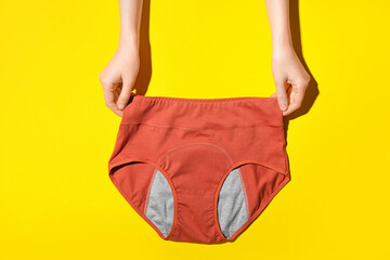 Woman holding period panties on yellow background