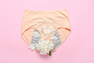 Period panties and beautiful peony flower on color background
