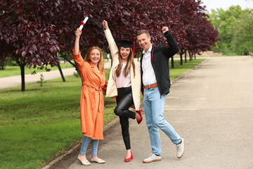Happy young woman with her parents on graduation day